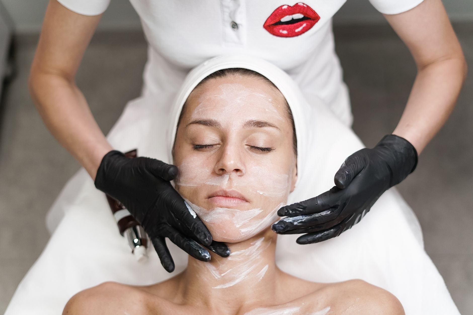 Esthetician applying a facial treatment to a relaxed client